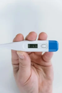 Person Holding White and Blue Thermometer at 38 4 c usfull for bacche ka bukhar kaise utare