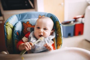 Little baby eating food with spoon