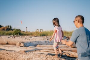 a girl playing with his father on rock