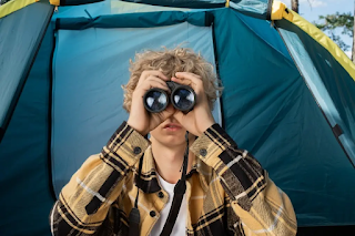 a teenage boy watching through binocular at camping