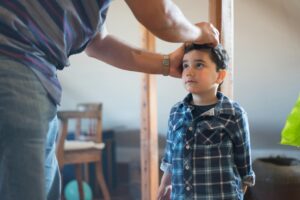 A father measuring his son's height on wall scale
