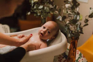 a newborn bath given by mother in a bathtub