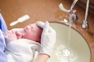 a newborn receiving head bath in a wash basin