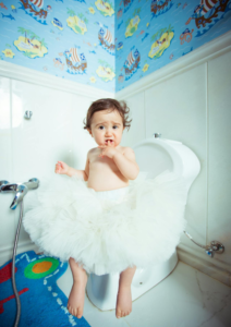 a baby sitting on commode in bathroom Child may take very long to pass stool.