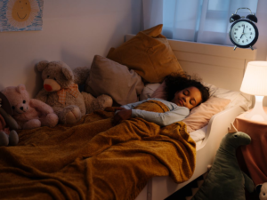 a girl sleeping in bedroom with bed wetting alarm clock ringing